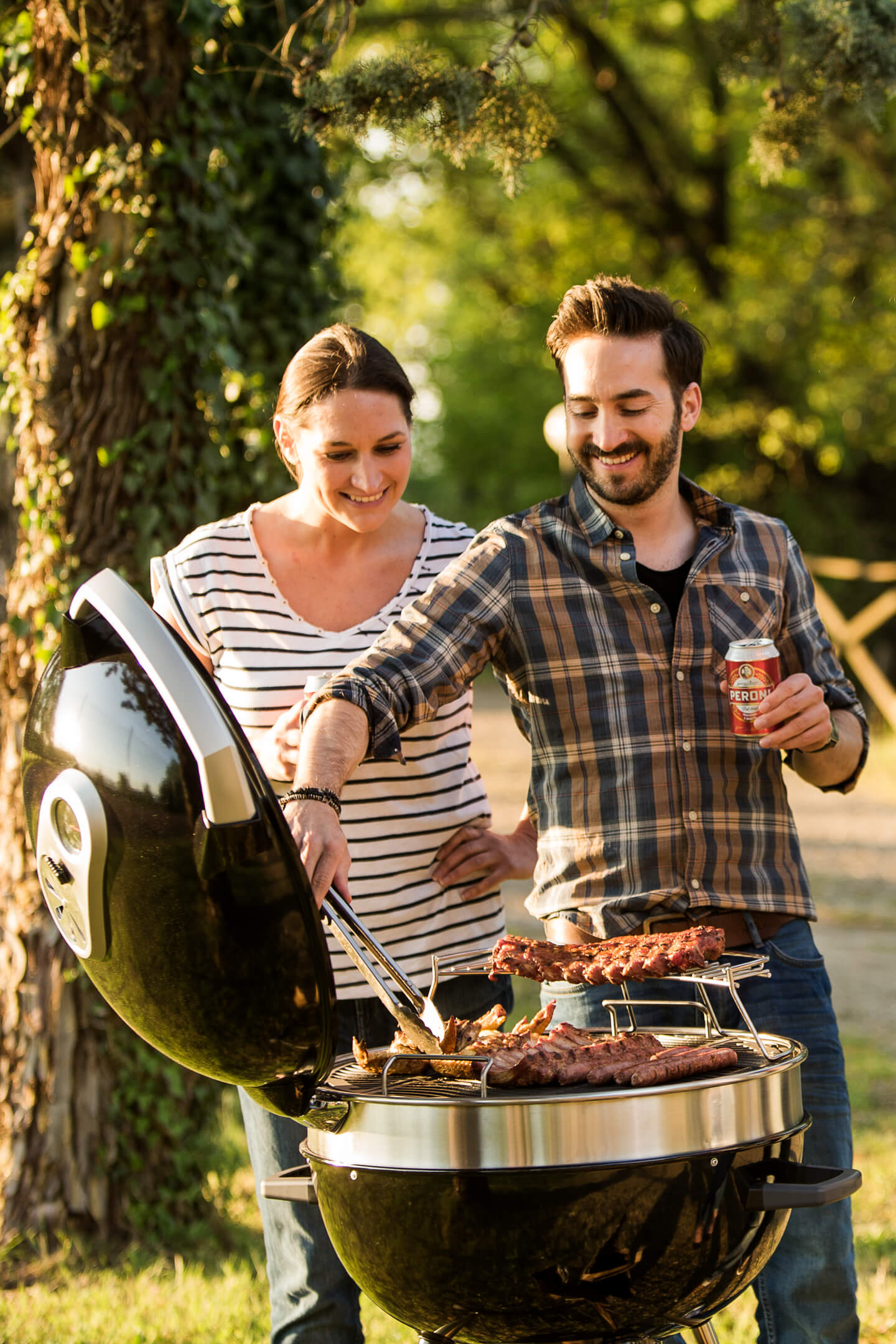 Foto van 2 mensen die grillen op een Napoleon houtskool-grill. De foto hoort bij de bbq tips.